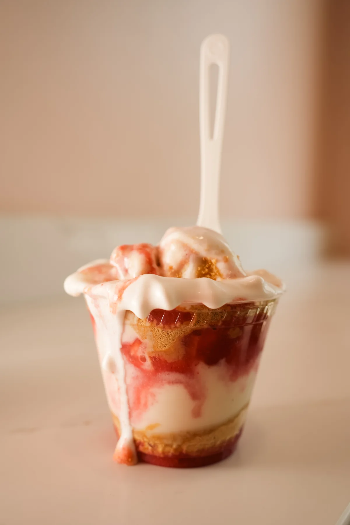 Soft-serve ice cream with fruit topping in a clear cup